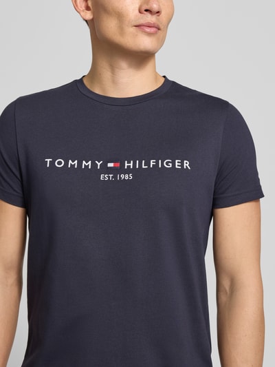 Männermodel trägt T-Shirt aus Bio-Baumwolle von Tommy Hilfiger, Gerader Schnitt, Rundhalsausschnitt, Logo-Stickerei, Nahaufnahme Oberkörper.