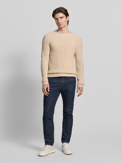 Männermodel trägt Strickpullover aus Baumwoll-Kaschmir-Mix mit gerippten Abschlüssen van FTC-Cashmere, regular fit, beige, effen textuur, volledig lichaam vooraanzicht.