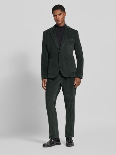 Männermodel trägt Slim Fit Sakko aus Baumwoll-Mix in Cord-Optik Modell 'Nick' von Zuitable in Dunkelgrün, Ganzkörperansicht von vorne. Elastischer Stoff, Reverskragen, Brust- und aufgesetzte Taschen, 2-Knopfleiste, Struktur durch feine Cord-Textur, Länge 72 cm, Schulterbreite 45 cm, Ärmellänge 67 cm.