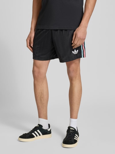 Männermodel trägt Regular Fit Sweatpants mit Label-Detail Modell 'Belgien 26' von adidas Originals in Optik: Unifarben aus Sweat, Nahaufnahme Unterkörper.