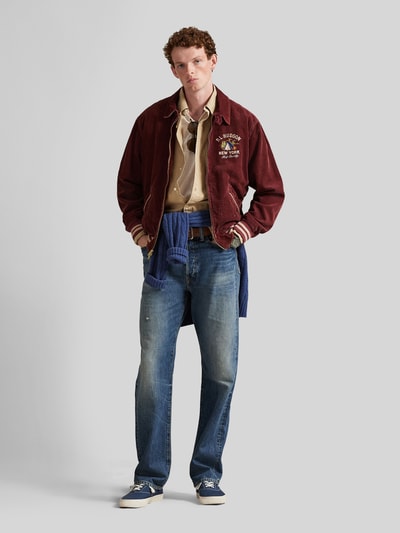 Męski model nosi Regular Fit Blouson aus Baumwoll-Cord od Polo Ralph Lauren w kolorze bordowym, sztruks, krój regular fit, logo, z kieszeniami i kołnierzem, całkowity widok z przodu.