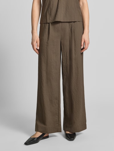 Frauenmodel trägt Stoffhose aus Viskose-Mix Modell 'TATU' von Mango, Wide Leg, elastischer Bund, braun, leichte Struktur, Nahaufnahme Unterkörper.