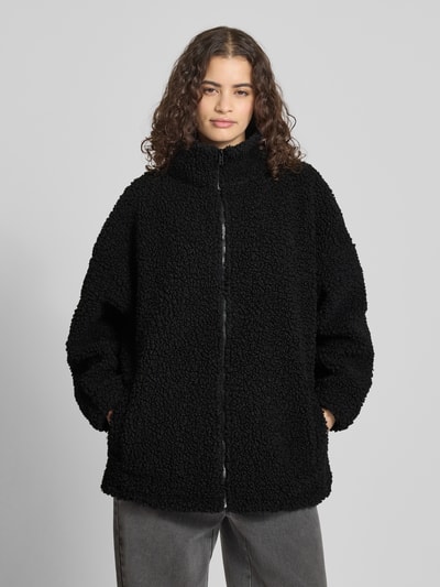 Frauenmodel trägt Jacke aus Teddyfell mit Stehkragen von Karo Kauer, schwarz, oversized, Reißverschluss, Vorderansicht, Ganzkörperansicht von vorne.