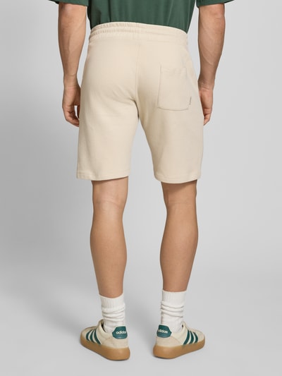 Männermodel trägt Straight Fit Shorts mit Logo-Stitching Modell 'Fillip' von Blend in Beige mit Strukturmuster aus Reine Baumwolle, Gesäßtaschen, elastischer Bund mit Tunnelzug, Ganzkörperansicht Rückansicht.