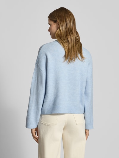 Frauenmodel trägt Relaxed Fit Strickpullover mit Crew Neck Modell 'SIMONI' von Only in hellblauem Melange, Stricktextur, lange Ärmel, gerippte Abschlüsse, Ganzkörperansicht Rückansicht.