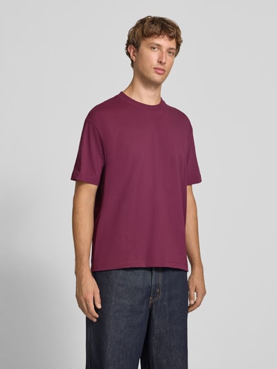 Männermodel trägt Relaxed Fit T-Shirt aus reiner Baumwolle von Marc O'Polo DENIM in Dunkelrot, dazu dunkle Jeans, Ganzkörperansicht von vorne.