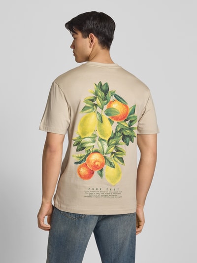 Männermodel trägt Regular Fit T-Shirt aus reiner Baumwolle Modell 'FRED' von Only & Sons in Beige mit Motiv-Print, Ganzkörperansicht Rückansicht.