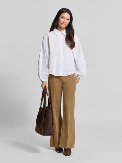 Frauenmodel trägt Wide Leg Cordhose aus Baumwoll-Mix Modell 'MAINE' von Brax in Beige, kombiniert mit weißer Bluse, Damen Cordhose, Ganzkörperansicht von vorne.