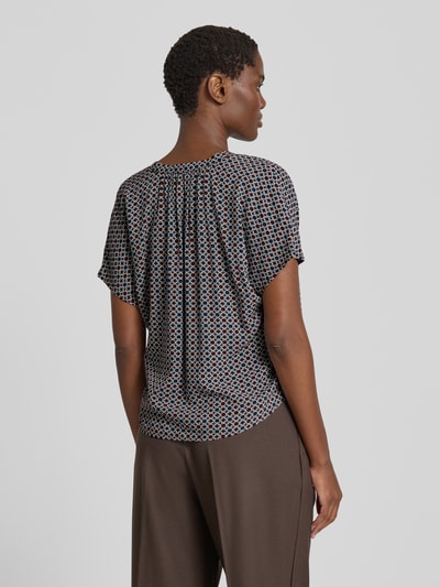 Vrouwenmodel draagt Blusenshirt aus Viskose mit Serafino-Ausschnitt van zero, zuiver viscose, loose fit, kapmouwen, ruglengte bij maat 36 56 cm, veelkleurig geometrisch patroon, gladde textuur. Ganzkörperansicht Rückansicht.