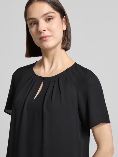 Frauenmodel trägt Blusenshirt mit Schmetterlingsärmeln und Schlüsselloch-Ausschnitt von Comma, schwarze Farbe, Loose Fit, Raffungen, Nahaufnahme Oberkörper, Rückenlänge bei Größe 36: 66 cm, Ärmellänge bei Größe 36: 16 cm.