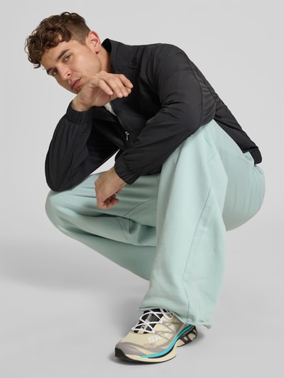Männermodel trägt Sneaker mit Kontrastbesatz von MM6 Maison Margiela in Beige mit strukturierter Sohle, Label-Details, Nahaufnahme Oberkörper. Herren Sneaker, abgerundete Form, Schnürverschluss, Absatzhöhe 4 cm, Schafthöhe 8 cm, Größe 44.
