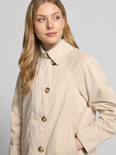Vrouwenmodel draagt Jacke mit seitlichen Eingrifftaschen und Kentkragen van Fuchs Schmitt in beige, knoopsluiting, recht model, kentkraag, raglanmouwen, steekzakken, ruglengte maat 36: 64 cm, schouderbreedte 38 cm, borstwijdte 51 cm, mouwlengte 44 cm. Nahaufnahme bovenlichaam, voorkant.