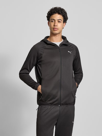 Männermodel trägt schwarze Regular Fit Trainingsjacke mit Logo-Print von PUMA PERFORMANCE, Kapuze, Reißverschluss, Eingrifftaschen, elastische Abschlüsse, Ganzkörperansicht von vorne.