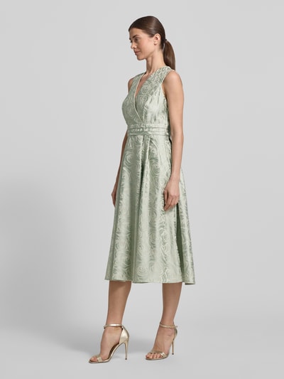 Modelka nosi Regular Fit Midikleid mit floralem Allover-Stitching von Rinascimento, jasna mięta, wzór kwiatowy, długość midi, bez rękawów, dekolt V, rozkloszowany dół, asymetryczny przód, zamek z tyłu, szerokość w rozmiarze S: 40 cm, długość tyłu w rozmiarze S: 97 cm, pełny widok z przodu.