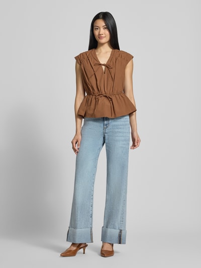 Frauenmodel trägt Wide Fit Jeans aus reiner Baumwolle Modell 'Rey' von GUESS in hellem Blau, 5-Pocket-Design, Ganzkörperansicht von vorne.