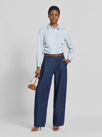 Modelka prezentuje jasnoniebieską Regular Fit Langarmbluse mit Hemdblusenkragen von Calvin Klein Womenswear, ciemnoniebieskie spodnie, brązowe buty i torebkę, pełen widok z przodu.