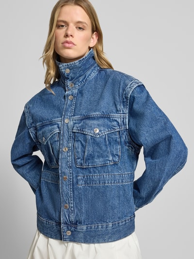 Frauenmodel trägt Jeansjacke mit Pattentaschen Modell 'Isabel' von Gina Tricot, Reine Baumwolle, Straight Fit, Druckknopfverschluss, Nahaufnahme Oberkörper.