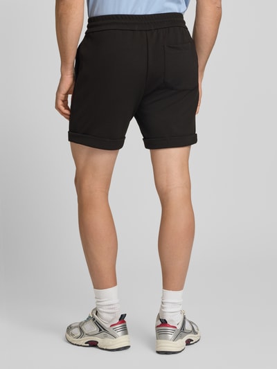 Männermodel trägt Regular Fit Shorts mit Viskose-Anteil Modell 'NEWKODYL' von Only & Sons, Melange-Optik, Nadelstreifen-Muster, Gesäßtasche, Beinabschluss: fixierter Umschlag, Bundabschluss: elastisch mit Tunnelzug, Eingrifftaschen, Ganzkörperansicht Rückansicht.