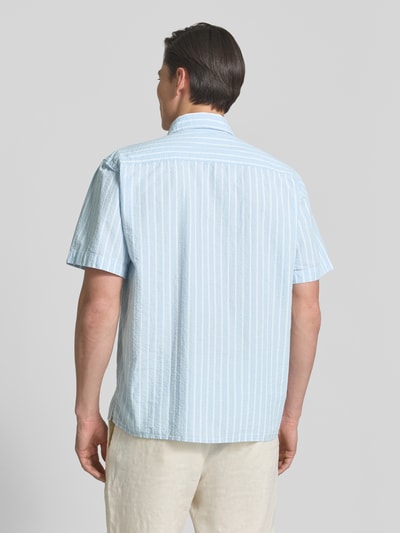 Männermodel trägt Relaxed Fit Freizeithemd aus reiner Baumwolle Modell 'STUART' von SELECTED HOMME, hellblau-weiß gestreift, Ganzkörperansicht Rückansicht.