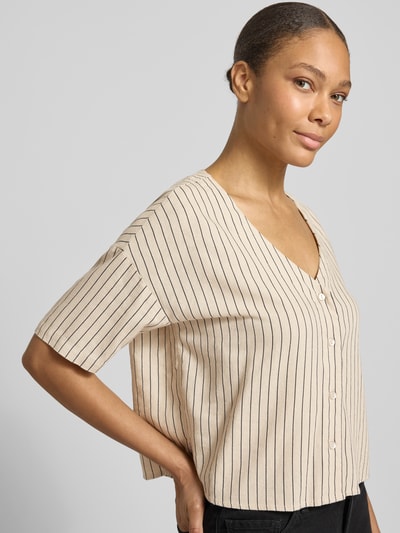 Modelka nosi Boxy Fit Hemdbluse aus Viskose-Leinen-Mix Modell 'MYMILO' od Vero Moda, kremowe tkanina z czarnymi paskami, 3/4 rękaw, flammgarn, dekolt w serek, tunikowy kołnierzyk, widok na górną część ciała z przodu.