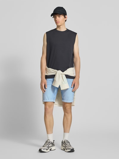 Męski model nosi Regular Fit Jeansshorts aus Baumwoll-Mix Modell 'PLY' von Only & Sons, stylizowana na denim, krój regular fit, aplikacja: naszywka z logo, detale: szlufki na pasek, zakończenie nogawek: nogawka z mankietem, 5 kieszeni, materiał: mieszanka bawełny, jasnoniebieski, gładka tekstura, ganzkörperansicht von vorne.