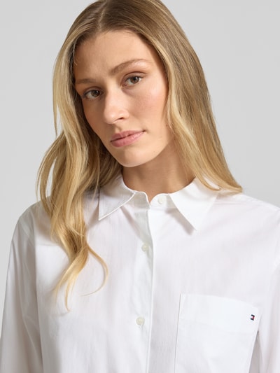 Frauenmodel trägt Regular Fit Langarmbluse aus reiner Baumwolle von Tommy Hilfiger, Optik: Unifarben, Logo-Stitching, Popeline, Nahaufnahme Oberkörper.