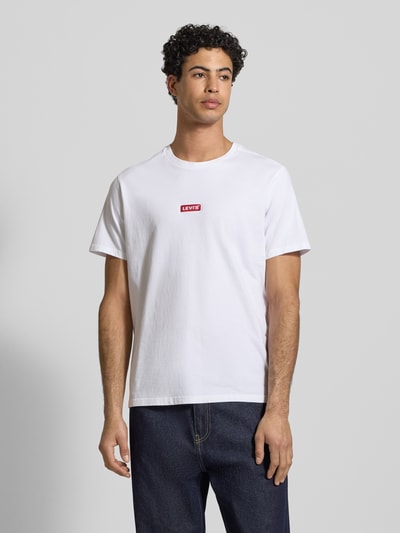 Männermodel trägt T-Shirt mit Label-Detail von Levi's®, weiße Farbe, Reine Baumwolle, Relaxed-Fit, Gerippter Rundhalsausschnitt, Ganzkörperansicht von vorne. Rückenlänge bei Größe M: 70 cm.