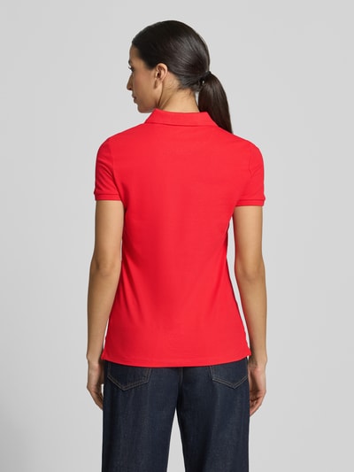 Frauenmodel trägt Slim Fit Poloshirt mit Knopfleiste von Christian Berg Woman aus Baumwoll-Elasthan-Mix in Rot, Rückenlänge 62 cm, Ganzkörperansicht Rückansicht.