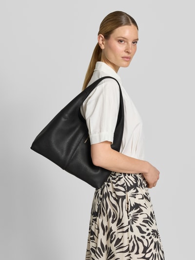 Vrouwenmodel draagt zwarte Handtasche mit Label-Detail Modell 'Alltime Lover M' van Hey Marly met ritssluiting en handvat, zijdeaanzicht, context: hoofdvak met ritssluiting, binnenvak met rits, breedte 31 cm, lengte 25 cm, diepte 12 cm, schouderriem 55 cm.