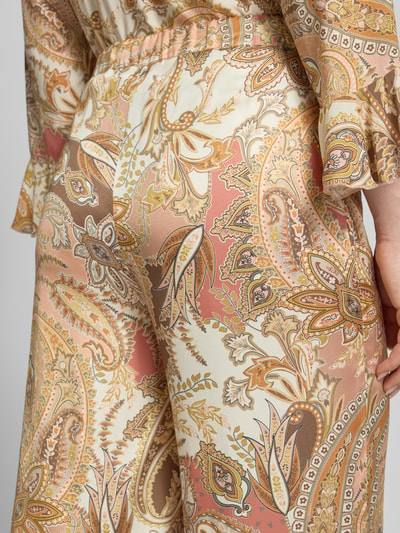 Frauenmodel trägt Stoffhose aus Viskose mit Paisley-Muster Modell 'Pia' von monari, Creme-, Beige- und Brauntöne, Nahaufnahme Rückansicht. Damen Regular-Fit, Elastischer Bund, Bundweite 34 cm, Innenbeinlänge 83 cm Größe 36.