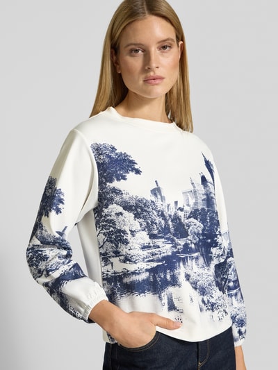 Vrouwenmodel draagt Sweatshirt im Allover-Look mit Rundhalsausschnitt van monari in wit en blauw, materialmix met stretch, regular fit, alloverprint, ronde halslijn, nahaufnahme bovenlichaam.