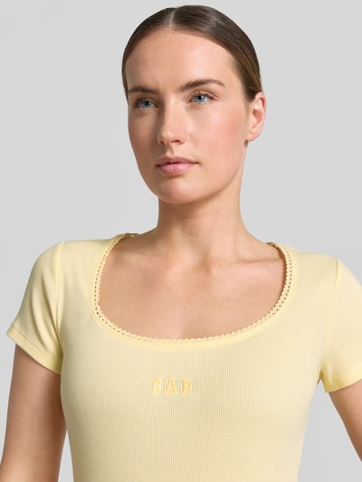 Frauenmodel trägt T-Shirt mit Logo-Stitching von GAP in Gelb aus Baumwoll-Mix mit Stretch-Anteil, Rundhalsausschnitt, körpernahe Passform, Nahaufnahme Oberkörper.