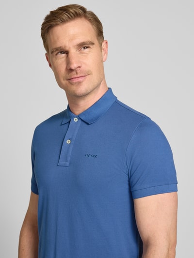 Männermodel draagt Slim Fit Poloshirt mit Logo-Stitching van Geox in blauw, puur katoen, structuurpatroon, polokraag, korte mouw. Nahaufnahme oberkörper.