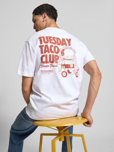 Männermodel trägt weißes Relaxed Fit T-Shirt aus reiner Bio-Bio-Baumwolle Modell 'FRED' von Only & Sons mit rotem Rücken-Print, Ganzkörperansicht Rückansicht.