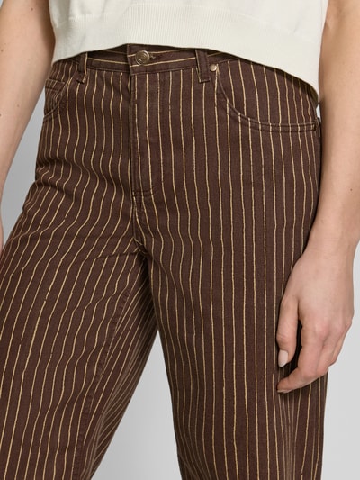 Frauenmodel trägt Straight Fit Jeans im 5-Pocket-Design Modell 'Florchi' von Mango aus Reine Baumwolle mit braun-gelben Streifen, Nahaufnahme Oberkörper.