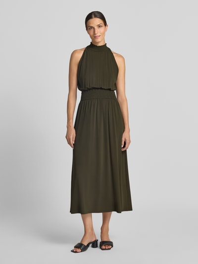 Frauenmodel trägt Midikleid aus Viskose-Mix von Samsøe Samsøe in Olive mit Stehkragen und Smok-Detail, Ganzkörperansicht von vorne. Taillierte Passform, ärmellos, Rückenlänge ca. 127 cm, Brustweite ca. 36 cm.