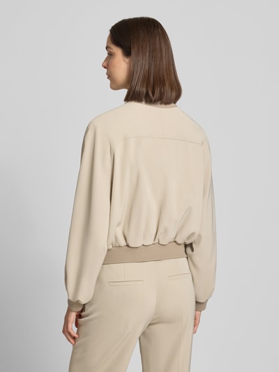 Frauenmodel trägt Jacke mit Pattentaschen Modell 'MARHAM' von Drykorn in Beige, Material-Mix mit Stretch, Ganzkörperansicht Rückansicht.
