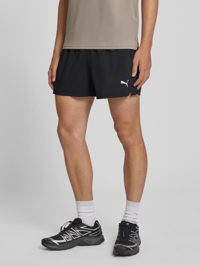 Männermodel trägt schwarze Regular Fit Sportshorts mit Logo-Print Modell 'TAD ESSENTIALS' von PUMA, Herren Sportshorts, Nahaufnahme Oberschenkel.