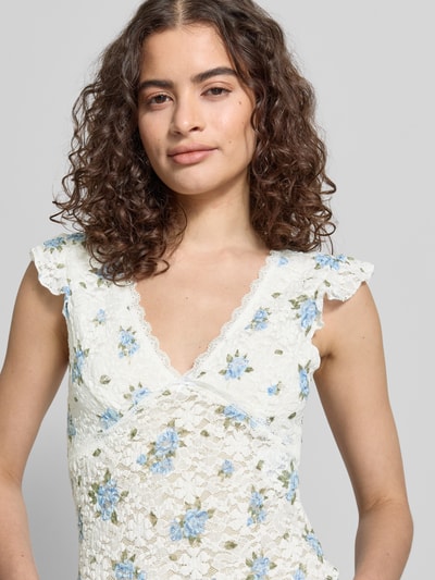 Frauenmodel trägt Slim Fit Top mit tiefem V-Ausschnitt Modell 'SAGA' von Only, florales Allover-Muster, Jersey, Kurzarm, Nahaufnahme Oberkörper.