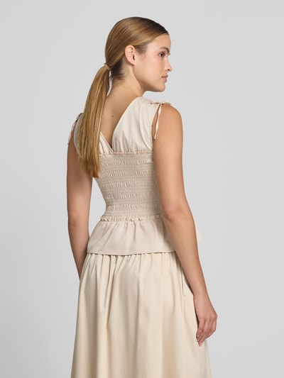 Frauenmodel trägt Blusentop mit Smok-Details von Comma, cremefarbener Baumwoll-Mix mit Stretch-Anteil, Regular-Fit, Rückenlänge 45 cm, Ganzkörperansicht Rückansicht.