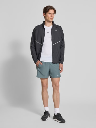 Männermodel trägt Shorts mit seitlichen Eingrifftaschen und Logo-Print von NIKE TRAINING in Grau, Loose-Fit, elastischer Bund, Ganzkörperansicht von vorne.