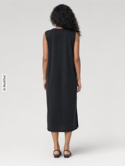 Frauenmodel trägt Midikleid aus Modal-Mix mit Rundhalsausschnitt von Jake*s Collection in Schwarz, gerader Schnitt, Seitenschlitz, Ganzkörperansicht Rückansicht.