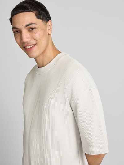 Männermodel trägt Oversized T-Shirt mit Strukturmuster von Pegador aus Baumwoll-Mix, Logo-Stitching, Rundhalsausschnitt, oversized, Nahaufnahme Oberkörper. Rückenlänge bei Größe M: 71 cm.