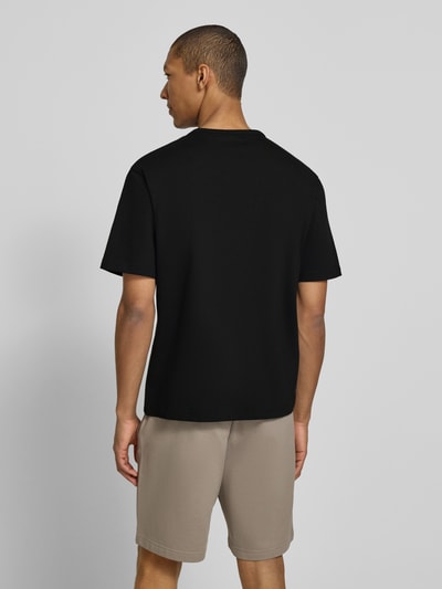 Männermodel trägt Regular Fit T-Shirt aus reiner Baumwolle Modell 'DOBUL' von HUGO, unifarben schwarz, Feinripp, Ganzkörperansicht Rückansicht.