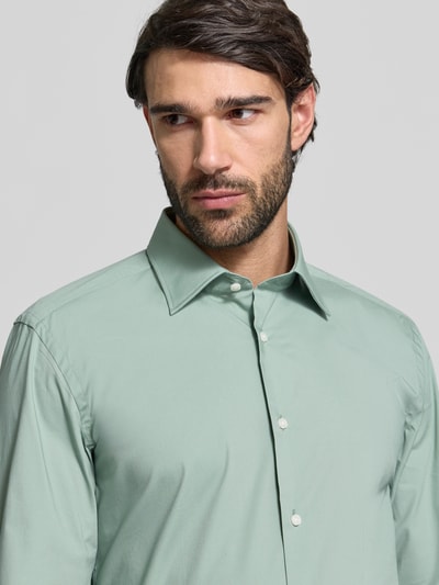 Męski model nosi Slim Fit Businesshemd aus Baumwoll-Mix Modell 'H-HANK-KENT' od BOSS w kolorze miętowym, gładki materiał, krój slim fit, kent kołnierzyk, długi rękaw, łatwe prasowanie, bawełniany miks, widok na górną część ciała z przodu.