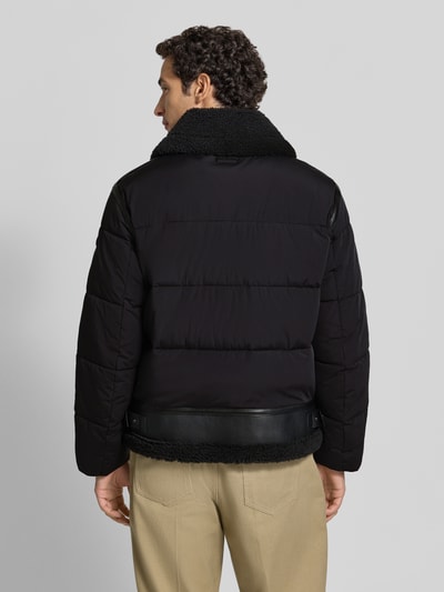 Männermodel trägt schwarze Steppjacke mit Zweiwege-Reißverschluss Modell 'FLINT' von khujo, Material-Mix, Ganzkörperansicht Rückansicht.