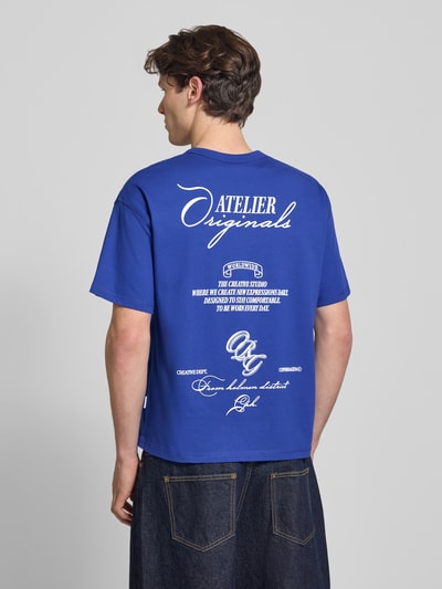 Męski model nosi Regular Fit T-Shirt mit überschnittenen Schultern von JACK & JONES z mieszanki bawełny, okrągły dekolt, nadruk z napisem na tyle, długość tyłu w rozmiarze M: 66 cm, widok całej sylwetki od tyłu.