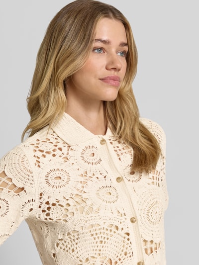 Kobiece model nosi Bluse in Häkel-Optik mit Knopfleiste von Milano Italy z bawełny, prosty krój, wykładany kołnierz, półprzezroczysty materiał, kremowe kolory, wzory imitacja wykonania na szydełku, długość tyłu 54 cm, długość rękawów 26 cm, widok na górną część ciała z przodu.