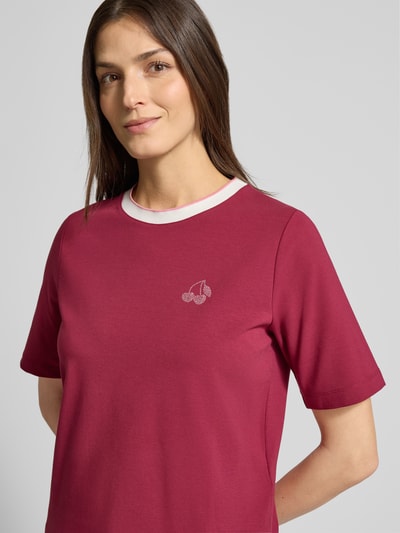 Vrouwenmodel draagt Regular Fit T-shirt met strass-steentjes van Marc Cain in bessenrood, mix van katoen en modal, ronde hals, Nahaufnahme Oberkörper.