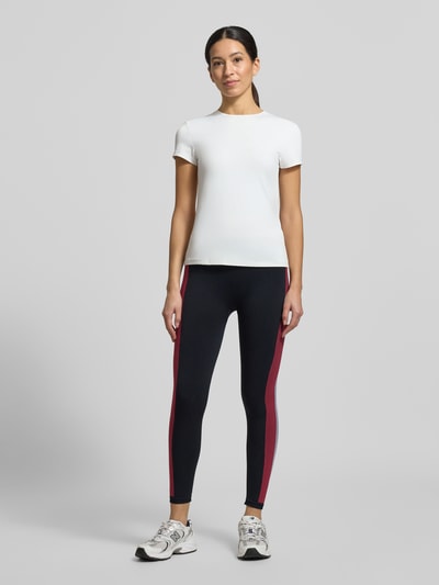 Frauenmodel trägt Leggings mit Galonstreifen Modell 'SEAMLESS' von Tommy Hilfiger in Dunkelblau mit kontrastfarbenen Streifen, enganliegend, Material-Mix mit Stretch, elastischer Bund, Label-Details, Ganzkörperansicht von vorne.